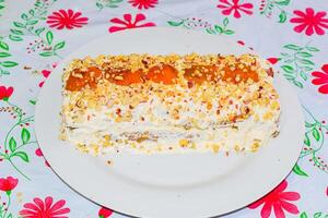 Cake with cream, apricot, sprinkled with nuts photo