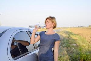 The girl quenches his thirst. Blonde drinks water from a plastic bottle. photo