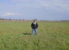 un hombre en un chaqueta en un campo de tulipanes claro con tulipanes foto