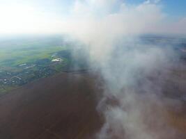 The smoke over the village. Clubs of smoke over the village houses and fields. Aerophotographing areas photo