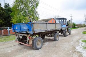 tractor with a rubble cart for repairing the road. Feeding holes on the road. Street repair. photo