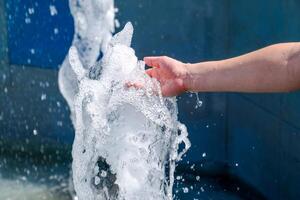 Hand touch the fountain. A stream of water from the fountain is touched by hand photo