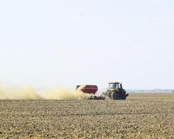 Tractor rides on the field and makes the fertilizer into the soi photo