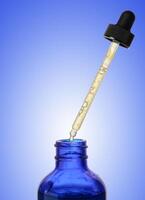 A glass blue bottle with a dropper on a blue background, a container for cosmetic products. photo