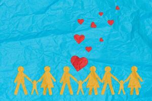 Cut out figures of a family dad, mom, and child holding hands on a blue paper background photo