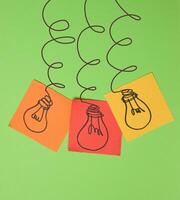 Drawn electric lightbulbs on paper sheets with a green background photo