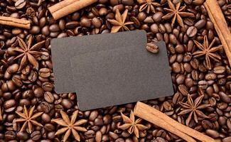 A black business card lies on scattered roasted coffee beans, space for an inscription photo