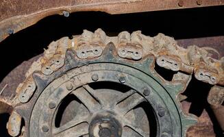 Fragment of a rusty caterpillar and wheel of a tank photo