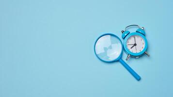 Alarm clock and magnifying glass on a blue background, symbolizing the concept of a deadline photo