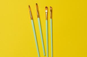 Brushes for painting with oil and watercolor paints on a yellow background photo