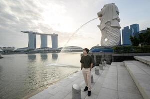 man in Merlion fountain in front of the Marina Bay photo