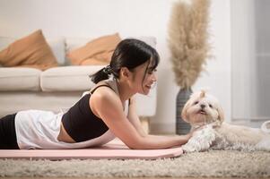 joven mujer en ropa de deporte haciendo meditación práctica y yoga con linda perro en vivo habitación, sano estilo de vida, mental salud concepto. foto