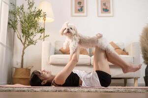 joven mujer en ropa de deporte haciendo meditación práctica y yoga con linda perro en vivo habitación, sano estilo de vida, mental salud concepto. foto