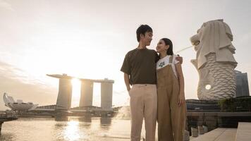 merlion fuente en frente de el centro de deportes acuáticos bahía playa con joven asiático Pareja de amor turista. foto