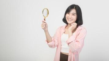 Young asian woman holding magnifying glass over white background, analysis and finance concept photo