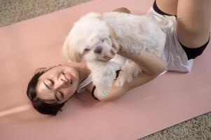 joven mujer en ropa de deporte haciendo meditación práctica y yoga con linda perro en vivo habitación, sano estilo de vida, mental salud concepto. foto