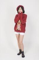 Young happy woman in santa claus hat wearing red sweater over white background, Christmas concept photo