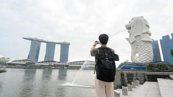 man in Merlion fountain in front of the Marina Bay photo