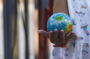 Girl's hands with a globe with a background of solar panels Concept of saving the world with renewable energy. photo