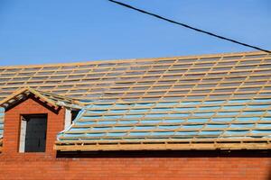 Construction of the roof of a new house. Wooden bars and vapor barrier photo