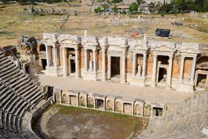 Ancient antique amphitheater in city of Hierapolis in Turkey. Steps and antique statues with columns in the amphitheater photo