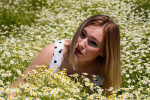 A woman in a white dress with polka dots is on a glade with daisies. Blooming daisies photo