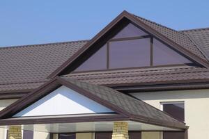 House with plastic windows and a brown roof of corrugated sheet photo