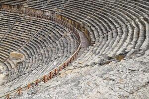 The steps of the amphitheater. Stone limestone and marble. Ancient antique amphitheater in city of Hierapolis in Turkey. Steps and antique statues with columns in the amphitheater photo