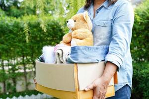 Volunteer collect cloth and doll in cardboard box to donate. photo