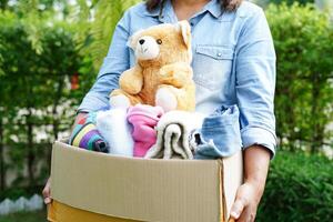 Volunteer collect cloth and doll in cardboard box to donate. photo