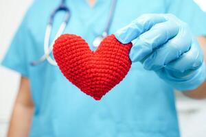 Asian woman doctor holding red heart for health in hospital. photo