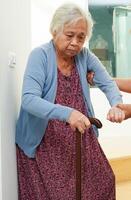 Asian senior woman use walking stick with caregiver help support walking down the stairs prevent accident, slip and fall at home. photo