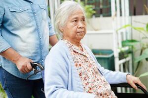 Caregiver help Asian elderly woman disability patient sitting on wheelchair in hospital, medical concept. photo