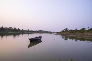 Beautiful Evening Landscape view of  Lake with a wooden boat under the blue sky photo