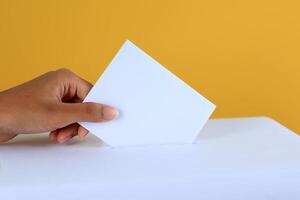 votación mujer cerca votación caja en amarillo color antecedentes foto