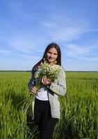 joven hermosa niña con un ramo de flores de manzanilla un mujer en un cebada campo foto