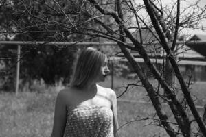 Black and white photo, girl in the garden on a meadow in a dress. photo