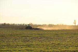 Tractor at sunset plow plow a field. Tilling the soil in the fall after harvest. The end of the season photo