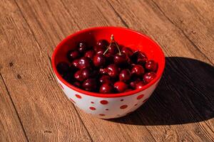 bayas de un dulce Cereza en un de madera antecedentes en un el plastico taza. maduro rojo dulce Cereza foto