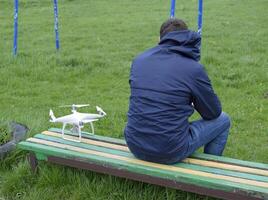 A man with a remote control quadroopter in his hands is sitting photo