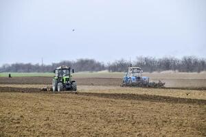 lozano y aflojar el suelo en el campo antes de siembra. el tractor arados un campo con un arado foto