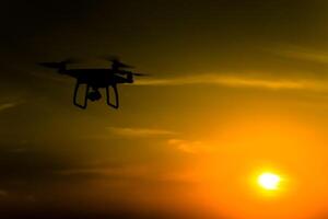 cuadricópteros silueta en contra el antecedentes de el puesta de sol. volador drones en el noche cielo foto