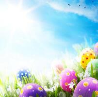 Art Easter eggs decorated with flowers in the grass on blue sky background photo