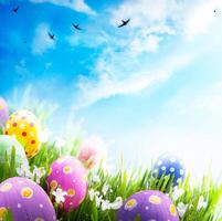 Art Easter eggs decorated with flowers in the grass on blue sky background photo