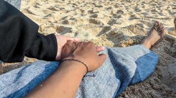 Holding hands lovingly while sitting on the beach photo