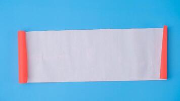 An orange rolled square paper is spread out into a blank white sheet on a light blue background. Crumpled blank white paper with copy space for text or advertising space. photo