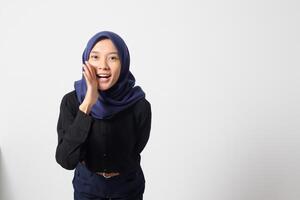 Portrait of excited Asian hijab woman in casual suit screaming announcement and whispering gossip. Businesswoman concept. Isolated image on white background photo