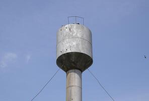 Silver Water Tower among green grass and trees photo