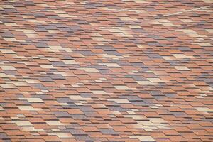 Roof from multi-colored bituminous shingles. Patterned bitumen shingles. photo