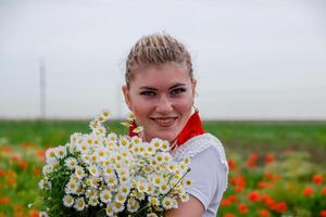 joven niña con un ramo de flores de margaritas en campo. margaritas en un amapola campo. foto